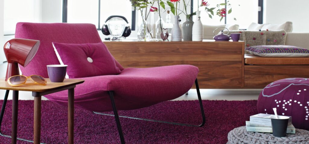 Ein Wohnzimmer mit einem lila Stuhl, bemalt mit harmonischen Farben, und einem Couchtisch. Thomas Jung Maler- & Stukkateurbetrieb aus Spiesen