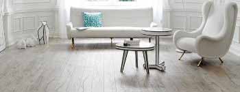 Ein Wohnzimmer mit weißen Möbeln und Holzböden, aufgewertet durch von einem Experten Maler ausgewählte Farben. Thomas Jung Maler- & Stukkateurbetrieb aus Spiesen